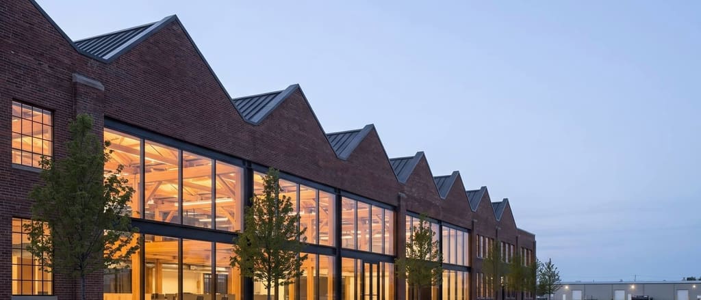Design visualization of Ashland Works, a former sawtooth-roofed tannery converted to workspace with its heavy-timber frame exposed.