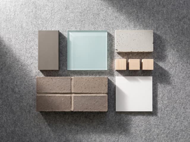 Visualization of a material sample board: brick coupon, glass square, precast panel chip, and basswood blocks on gray felt.